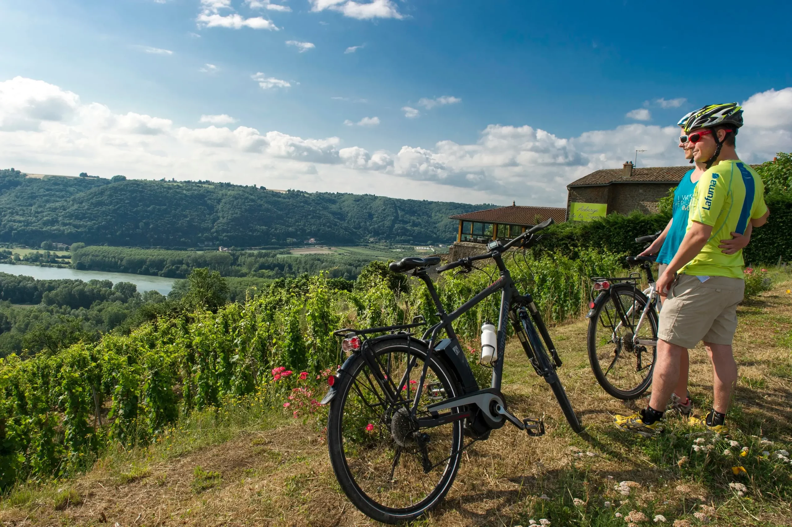 Cyclistes sur la piste cyclable de La Belle Via, traversant des paysages pittoresques entre montagnes, vignobles et rivières, offrant une escapade vélo immersive en Isère.