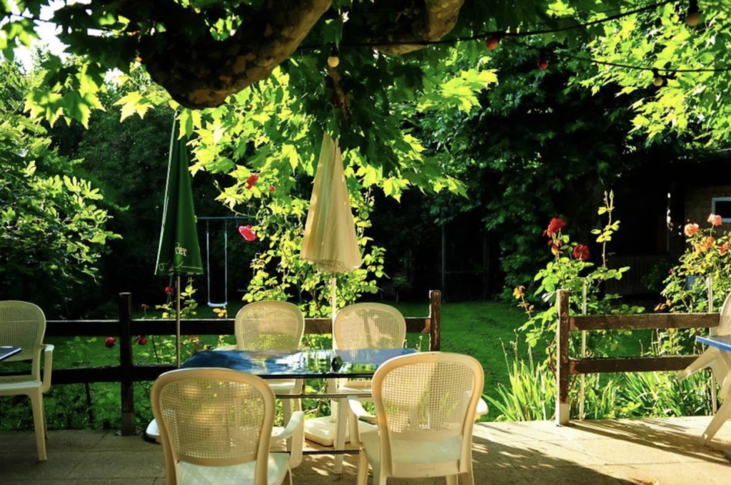 Image de l'Auberge de Choully à Satigny, située au cœur du vignoble genevois avec une terrasse ombragée, proposant 50 références de vins suisses.