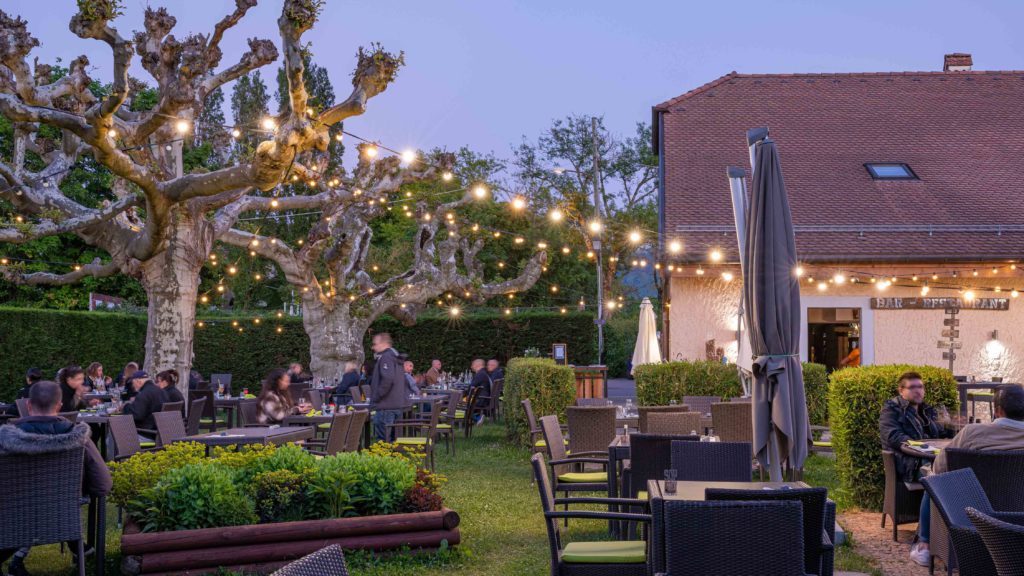 Cette charmante auberge possède un jardin verdoyant où l’on peut profiter de petits plats élaborés avec des produits locaux et de saison, à Plan-les-Ouates, en périphérie de Genève. Terrasses été 2024